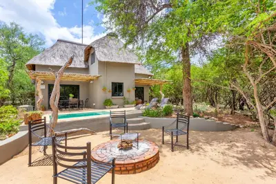 a patio with chairs and a table in front of a house at The Bush House in Hoedspruit