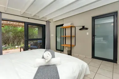 a bedroom with a large white bed and a window at The Bush House in Hoedspruit