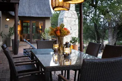 a table with a vase of flowers on a patio at Zebra Lodge in Hoedspruit