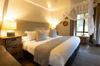 a bedroom with a large bed and a window at Zebra Lodge in Hoedspruit
