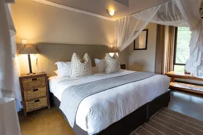 a bedroom with a large bed with white sheets and pillows at Zebra Lodge in Hoedspruit