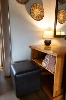 a stool and a table with a lamp and towels at Zebra Lodge in Hoedspruit