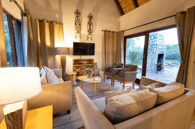 a living room with a couch and a tv at Zebra Lodge in Hoedspruit