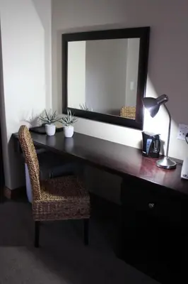 a desk with a mirror and a chair and a lamp at Mosate Lodge in Polokwane