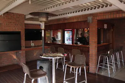 a bar with chairs and a table in a restaurant at Mosate Lodge in Polokwane