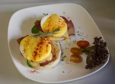 a plate of food with eggs and bacon and tomatoes at Beetleloop Guest House in Nelspruit