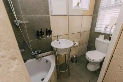 a bathroom with a sink and a toilet and a bath tub at Beetleloop Guest House in Nelspruit