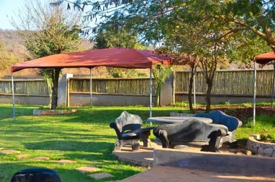 a patio with an umbrella and chairs in a yard at 1 OAK Resort in Thohoyandou
