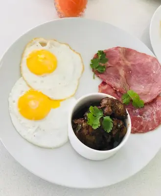 a plate of breakfast food with eggs sausage and meat at 1 OAK Resort in Thohoyandou