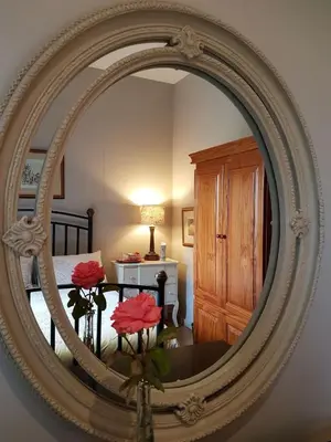 a mirror reflecting a bedroom with a bed and red flowers at MyAula in Tierpoort