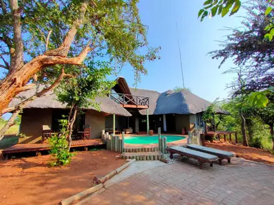 a house with a thatched roof and a swimming pool at Lions Place in Grietjie Nature Reserve