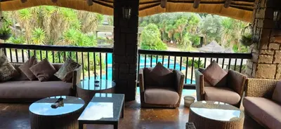 a living room with couches and tables and a large window at Bushmans Rock in Pretoria