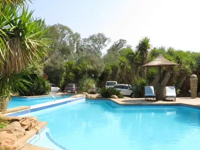 a large swimming pool with two chairs and a gazebo at Bushmans Rock in Pretoria