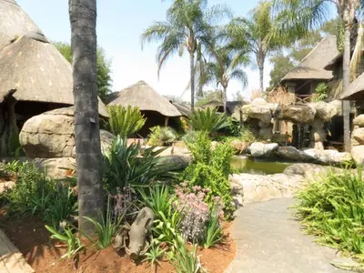 a garden with a pond and some palm trees at Bushmans Rock in Pretoria