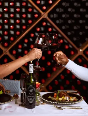 two people holding up a glass of wine on a table at Coach House Hotel & Spa Tzaneen in Tzaneen