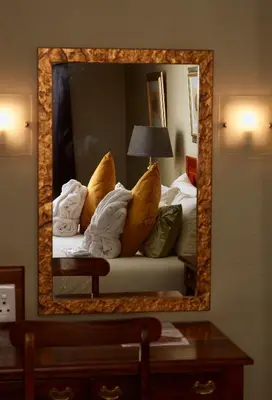 a mirror in a hotel room with a couch with pillows at Coach House Hotel & Spa Tzaneen in Tzaneen