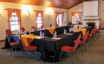 a conference room with long tables and red chairs at Coach House Hotel & Spa Tzaneen in Tzaneen