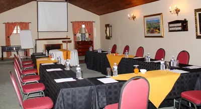 a conference room with tables and chairs and a screen at Coach House Hotel & Spa Tzaneen in Tzaneen