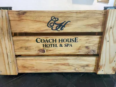a wooden sign for a beach house hotel and spa at Coach House Hotel & Spa Tzaneen in Tzaneen