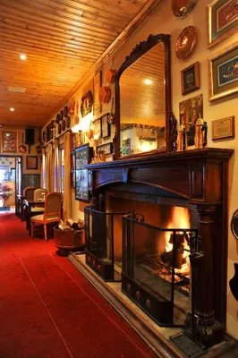 a living room with a fireplace and a mirror at Magoebaskloof Hotel in Tzaneen