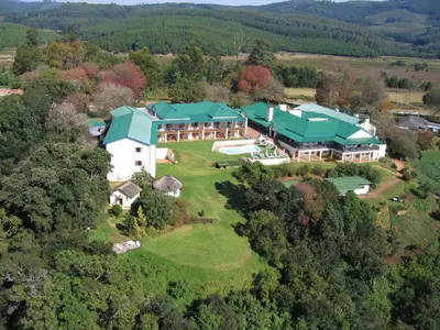 an aerial view of a large house with green roofs at Magoebaskloof Hotel in Tzaneen