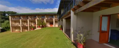 a building with a green lawn in front of it at Magoebaskloof Hotel in Tzaneen