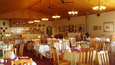 a dining room with tables and chairs and chandeliers at Magoebaskloof Hotel in Tzaneen