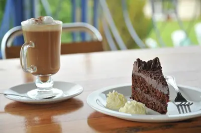 a piece of chocolate cake and a drink on a table at Magoebaskloof Hotel in Tzaneen