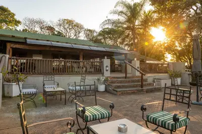 a group of chairs and tables in front of a building at Chestnut Country Lodge in Hazyview