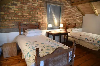 a bedroom with two beds and a brick wall at Molly's Cottage in Graskop