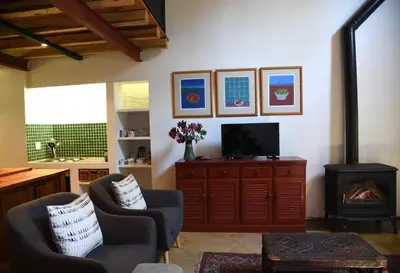 a living room with a tv and a stove at Molly's Cottage in Graskop