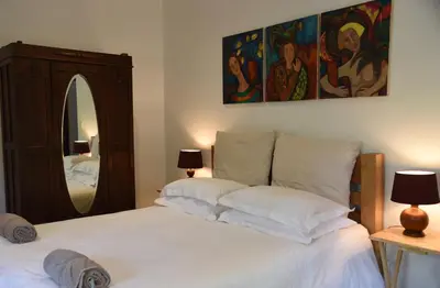 a bedroom with a large white bed with a mirror at Molly's Cottage in Graskop