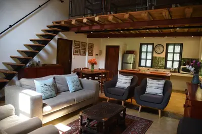 a living room with a couch and chairs and a staircase at Molly's Cottage in Graskop