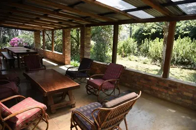 a covered patio with chairs and tables and a table at Molly's Cottage in Graskop