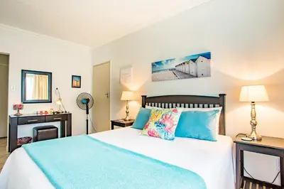 a bedroom with a large bed with blue pillows at LeoZet Self catering apartment in Pretoria