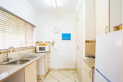 a kitchen with a sink and a refrigerator at LeoZet Self catering apartment in Pretoria