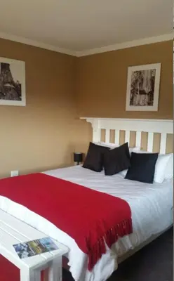 a bedroom with a large bed with a red blanket at Woodcutters Guest House in Haenertsburg