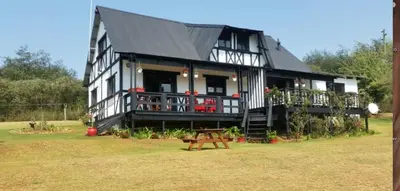a large black and white house with a deck at Woodcutters Guest House in Haenertsburg