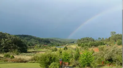 a rainbow over a field with a river and trees at Woodcutters Guest House in Haenertsburg