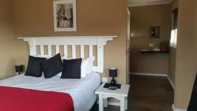 a bedroom with a bed with a red and white comforter at Woodcutters Guest House in Haenertsburg