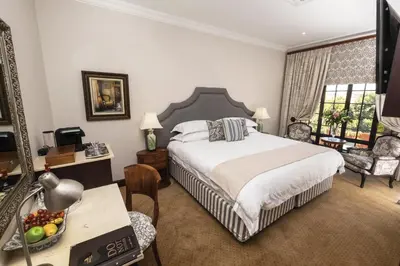 a bedroom with a bed and a desk with a mirror at Ivory Manor Boutique Hotel in Pretoria