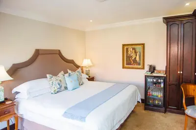 a bedroom with a white bed and a wooden cabinet at Ivory Manor Boutique Hotel in Pretoria