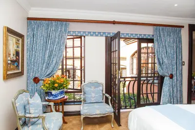 a bedroom with a bed and two chairs and a window at Ivory Manor Boutique Hotel in Pretoria