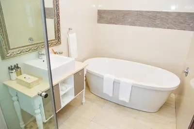 a white bathroom with a tub and a sink at Ivory Manor Boutique Hotel in Pretoria