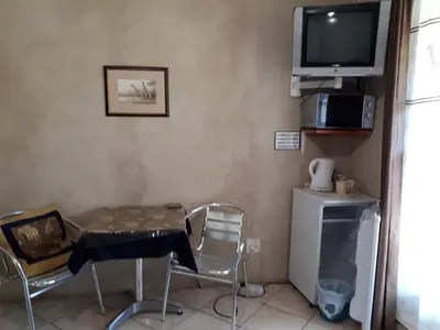a room with a table and chairs and a television at Vivian's Cottage in Pretoria