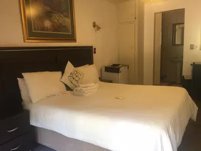 a bedroom with a bed with white sheets and pillows at Villa Grande Lodge in Louis Trichardt
