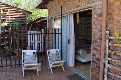 a patio with two chairs and a bed in a building at Grace Accommodation Centurion in Centurion