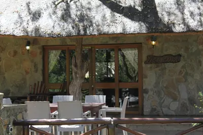 a restaurant with white chairs and a table and windows at Moholoholo Ya Mati in Kampersrus AH