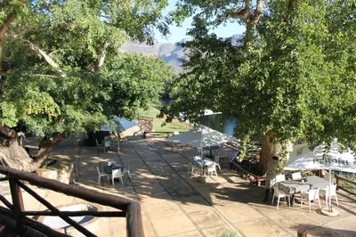 a patio with tables and chairs under some trees at Moholoholo Ya Mati in Kampersrus AH