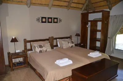 a bedroom with two beds and a desk and a window at Moholoholo Ya Mati in Kampersrus AH